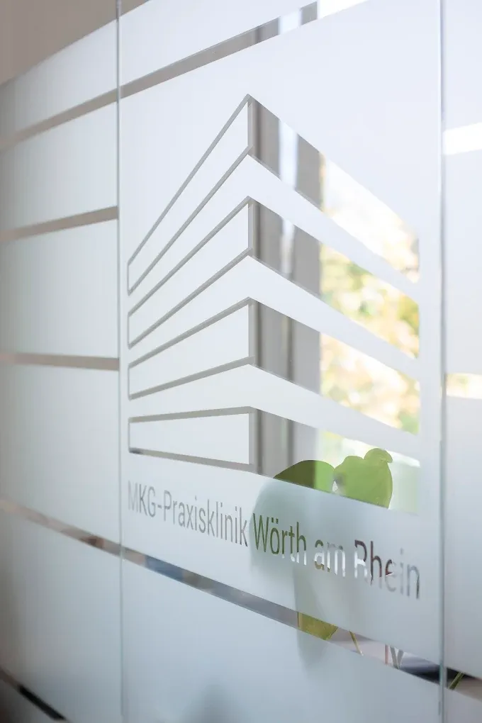 Logo der MKG-Praxisklinik auf Glastür